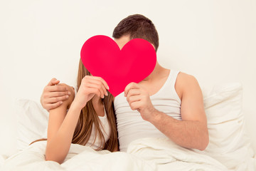 Poster - Portrait of man and woman kissing behind red paper heart