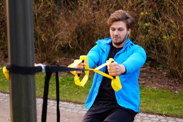 Wall Mural - Sporty male exercising with fitness trx.