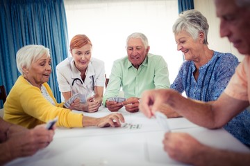 Wall Mural - Pensioners playing cards with nurse