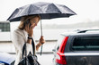 © Maskot - Businesswoman talking on smart phone during rainy season in city