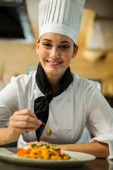 Wall Mural - Happy head chef garnishing pasta dish with olive