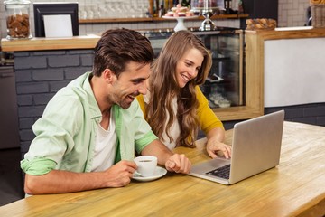 Wall Mural - Smiling couple using a laptop