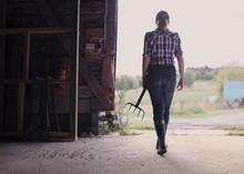 Woman Holding Pitchfork In Barn