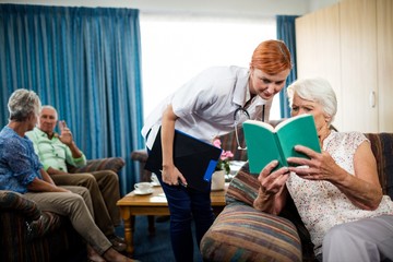 Wall Mural - senior woman reading book with nurse
