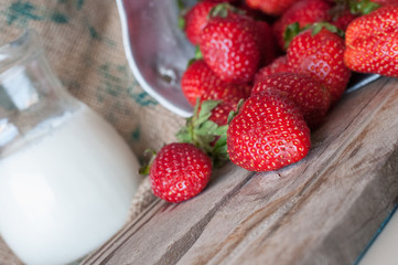 Ripe red strawberries and milk on wooden table