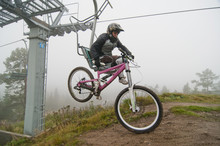 Woman In Sportswear Carrying Bicycle While Sitting On Ski Lift