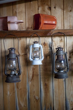 Oil Lamps Hanging On Shelf Against Wooden Wall