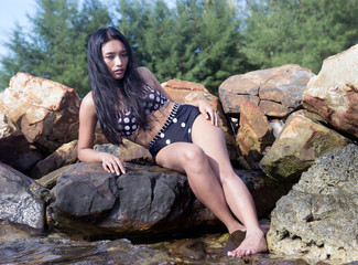 Wall Mural - woman in retro swimsuit sitting on the rocks at the water