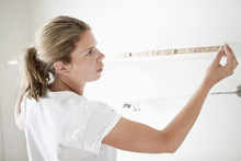 Woman Measuring Wall With Measuring Tape