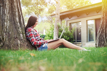 Canvas Print - Attractive young woman working on laptop under the tree on sunny