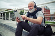 © ArtFamily - Stylish aged man in headphones with tablet computer sits on a si