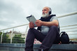 © ArtFamily - Stylish aged man in headphones with tablet computer sitting on a
