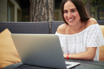 Wall Mural - Young smiling lady in the yard working on laptop