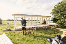 Man And Woman Making Shed At Farm Against Sky