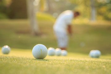 Golf ball and blurred of man playing golf in green course