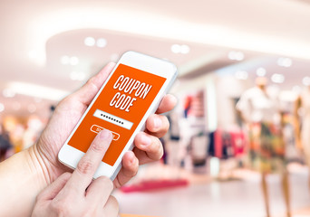 Aufkleber - Hand holding mobile phone with coupon code word with blurred sto