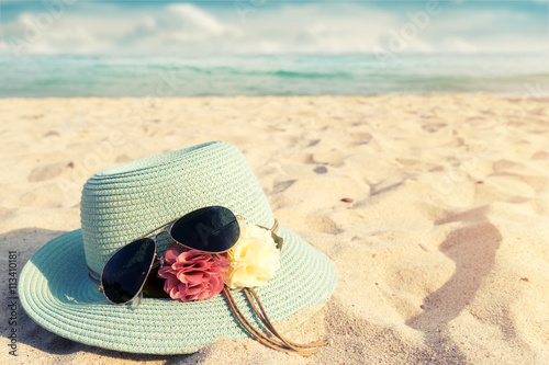 Fotografia Summer vacation concept with straw hat and sunglasses on sandy tropical beach -