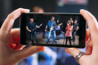 © golubovy - Music band performance photographing on smartphone. Closeup of smartphone screen with picture of young student rock band performance in sound recording studio