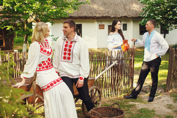 Wall Mural - Two wedding couples dressed in ethnic style pose on the backyard