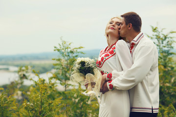 Wall Mural - A wedding couple in Ukrainian ethinc dressing kisses on the hill