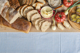 Fototapeta Kuchnia - Stół zastawiony chlebem, pomidorami, cebulkami i smalcem na śniadanie na stole z obrusem w kratę