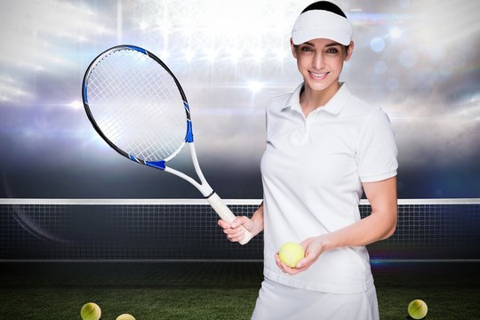Female athlete posing with a tennis racket against sports pitch