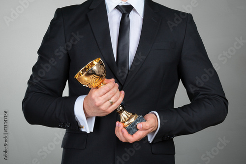 Fotografía El hombre de negocios que sostiene la taza trofeo de oro