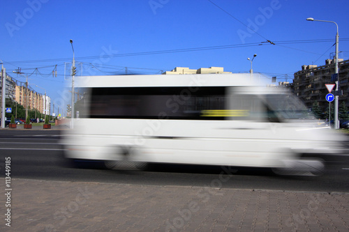 Fotografie, Obraz Motion white blurred minibus\Motion blurred white minibus on the street in the a