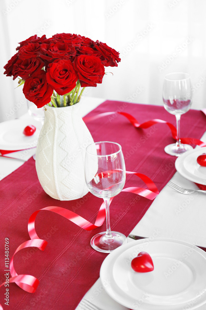 Vase with red roses on a holiday served table