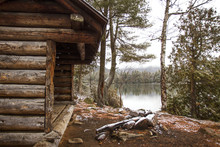 Old Log Cabin By Lake And Trees In Forest