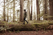 © Cavan Images - Side view of woman walking on fallen tree in forest