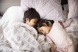 © Cavan Images - Siblings sleeping on bed