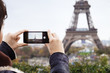 © Cavan Images - Young woman photographing Eiffel Tower with smart phone