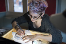 Female Tattoo Artist Drawing On Paper In Studio