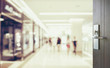 opened wooden door to blurred people shopping in department store with bokeh background.