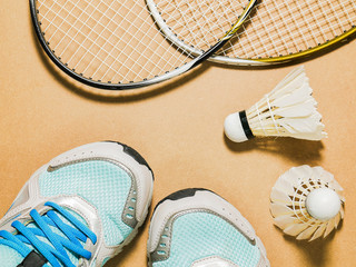 sports set of blue sport shoes and shuttlecocks with two badminton racket on plywood background