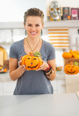 Wall Mural - Woman with ceramic pumpkin in halloween decorated kitchen