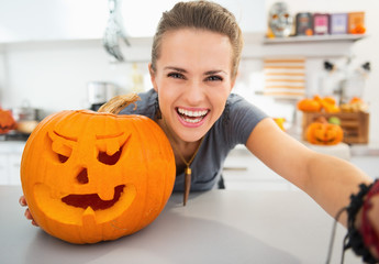 Wall Mural - Smiling young woman taking selfie in halloween decorated kitchen