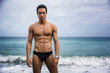 © theartofphoto - Young shirtless athletic man standing in water by ocean shore