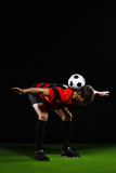Fototapeta Sport - Soccer player making trick with ball over black background