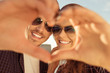 Cheerful romantic couple making heart gesture with hands
