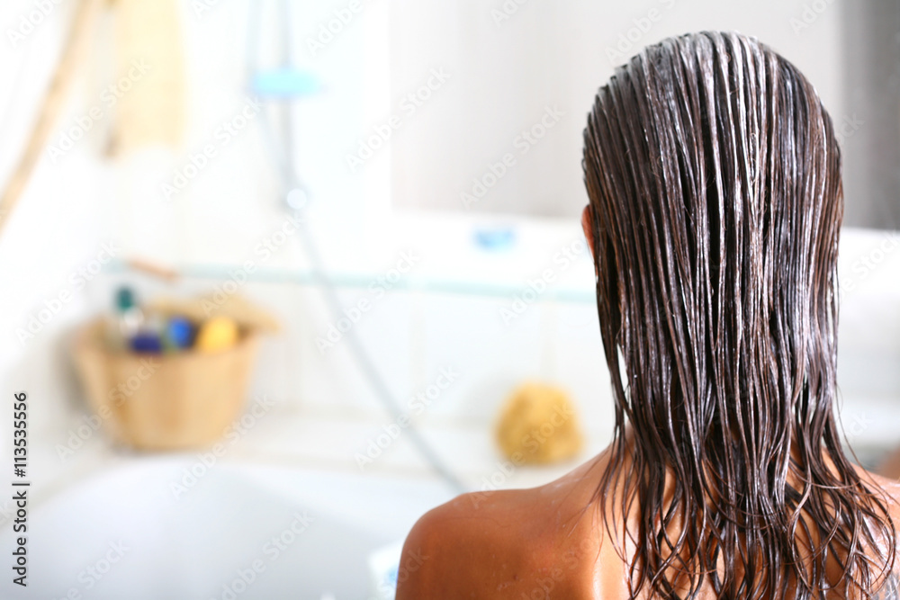 femme dans sa salle de bain soignant ses cheveux - obrazy, fototapety, plakaty 