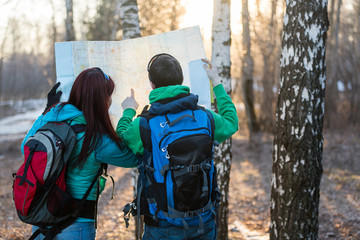 Young couple hikers looking at map.