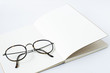 glasses on white page of opened notebook, white background