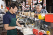 © Tyler Olson - Happy Man Watching Salesman Slicing Cheese In Shop