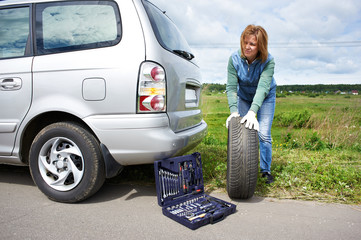 Wall Mural - Woman changing a wheel of car