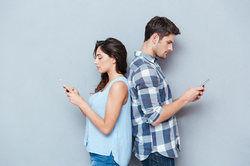 Canvas Print - Couple standing back to each other looking at the phone