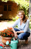 Fototapeta Kwiaty - Portrait of beautiful 40 years old woman gardening on sunny day