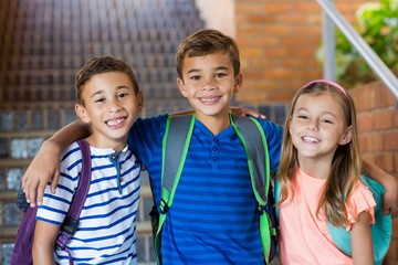 Wall Mural - Smiling school kids standing with arm around