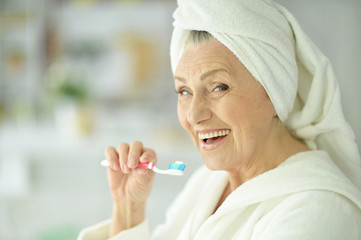 Canvas Print - elderly woman brushing her teeth 